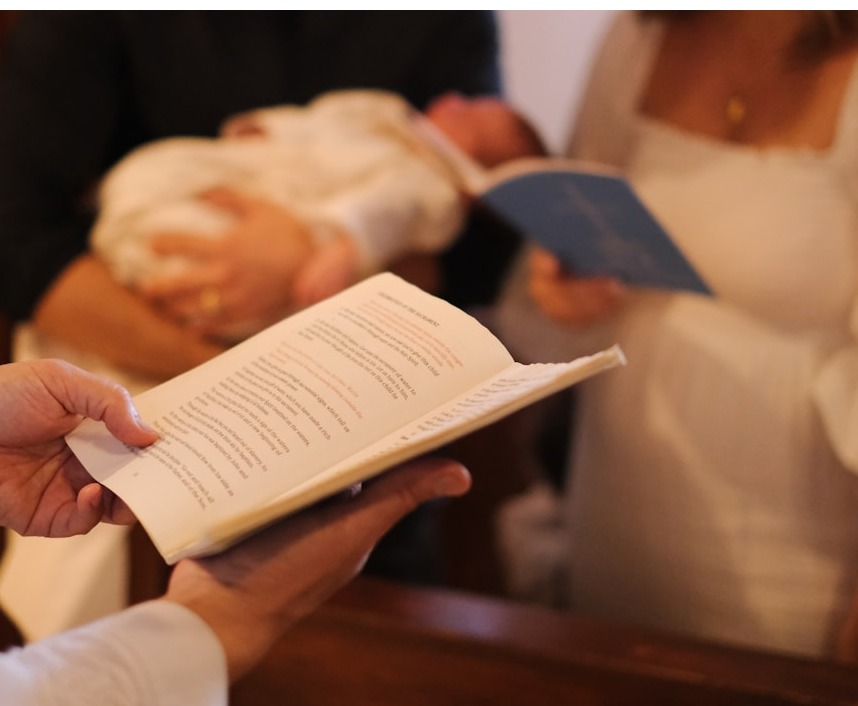 A close-up of hands shaking over a wedding contract, symbolizing agreement and trust. Background elements should include a wedding ring and a soft-focus wedding invitation, conveying a sense of partnership and understanding.