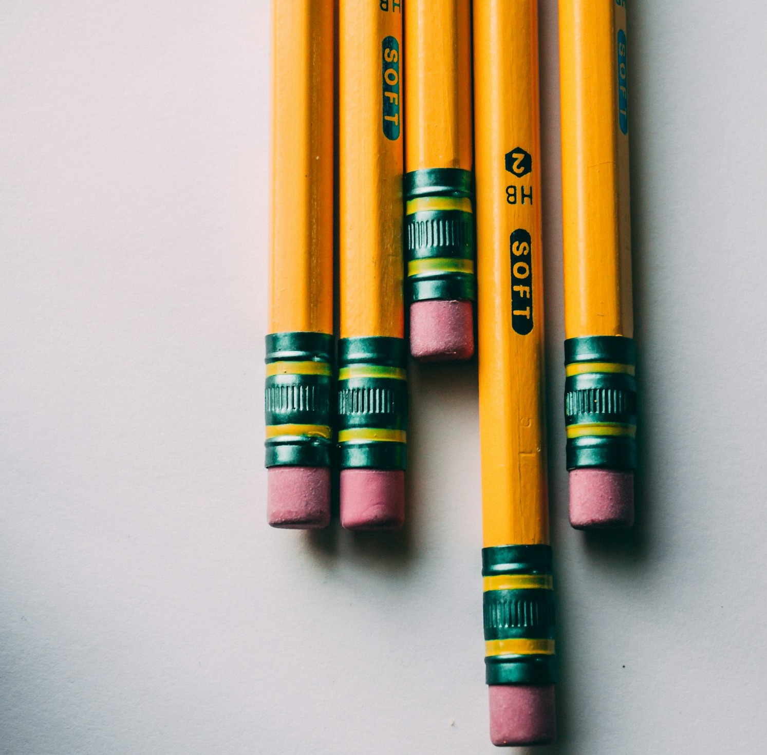 A young adult sitting thoughtfully at a desk, surrounded by books and a laptop, a vision board of various career paths and educational goals pinned up on the wall behind them.