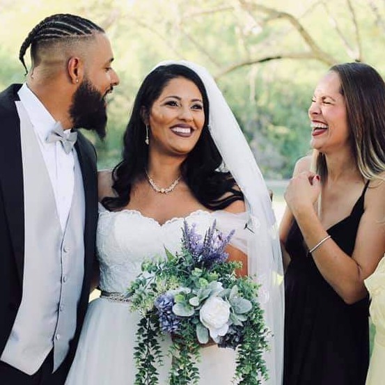 A picturesque outdoor wedding scene at golden hour, with a bride and groom sharing a tender moment under a floral arch. Surrounding guests are joyfully celebrating, with soft sunlight illuminating the happy expressions and details of the wedding decor.