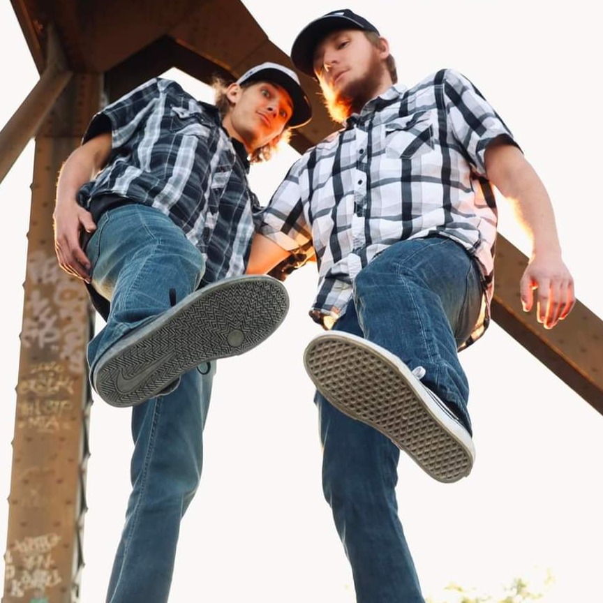 A stunning photoshoot set in an urban environment, featuring a male and female model styled in fashionable attire. The scene showcases vibrant graffiti art in the background, with direct sunlight casting dynamic shadows, creating a fashionable and artistic atmosphere.