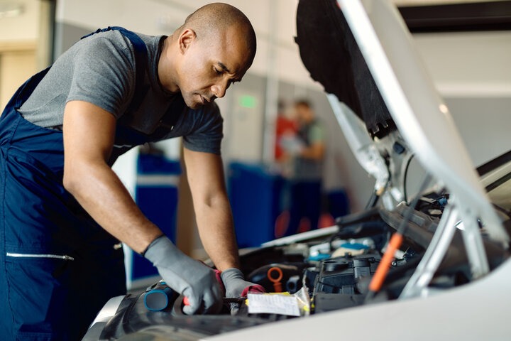 A close-up photorealistic image of a mechanic expertly working on an engine. Focus should be on the engine components and the mechanic's hands, showcasing their skill and precision. Lighting is directed to highlight the engine details. Colors should be professional and emphasize the mechanical aspects. Technical specs: 4K resolution.
