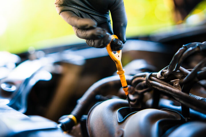 A photorealistic image of a mechanic performing an oil change on a car. The focus should be on the process of draining the old oil and replacing the oil filter. The lighting is bright and clean. Color palette emphasizes the process of an oil change. Technical specs: 4K resolution.