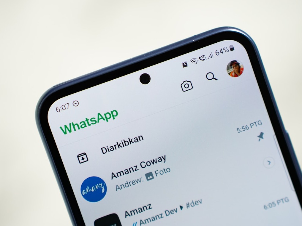 A photorealistic image of a smiling customer service representative sitting at a desk, looking directly at the camera with a friendly expression. The desk is clean and organized with a laptop displaying a website contact form. The background is a modern office setting with natural light.