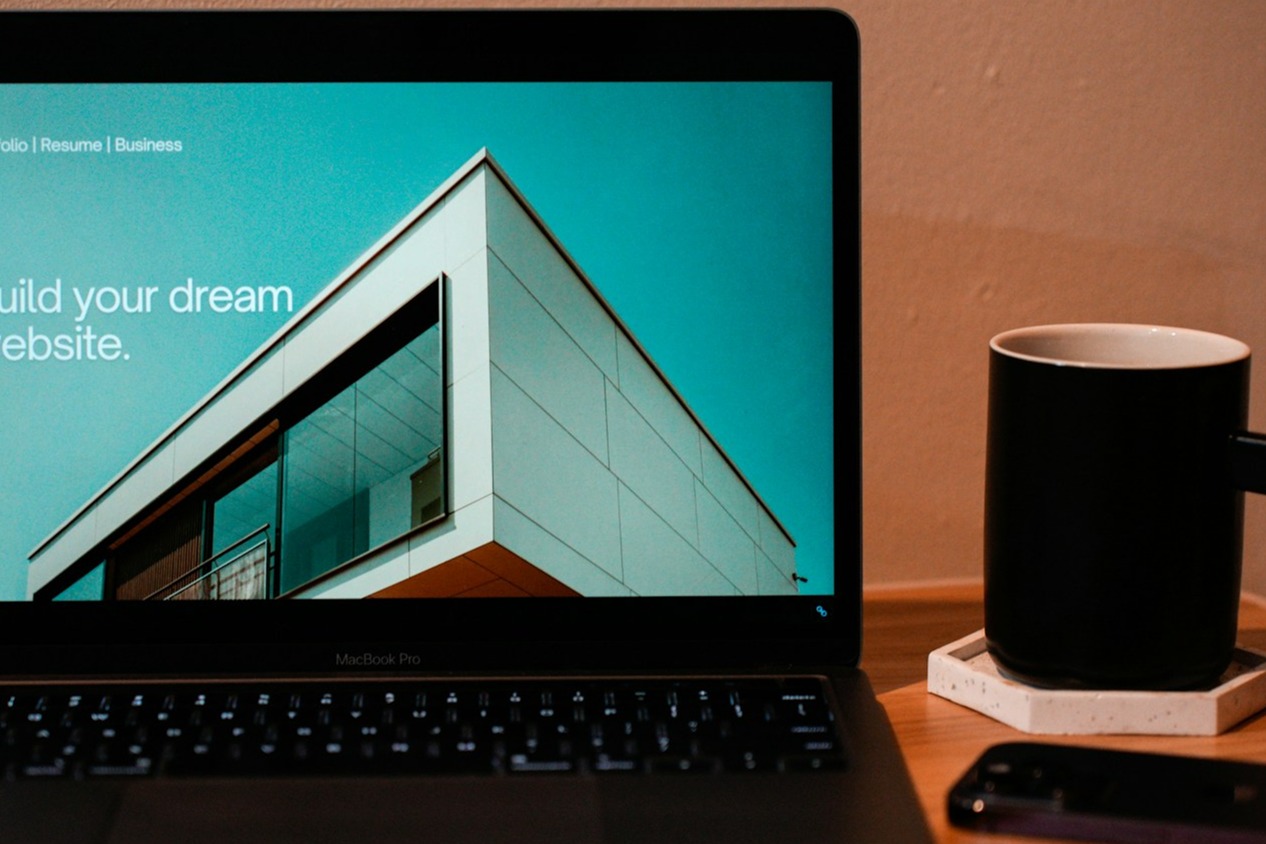 A close-up view of a designer's hands working on a computer screen, showcasing a sleek and modern website design. The screen displays a website mockup with captivating visuals and easy navigation, representing a user-friendly experience. The surrounding environment features a minimalist workspace with design elements, books, and plants, emphasizing creativity and innovation.