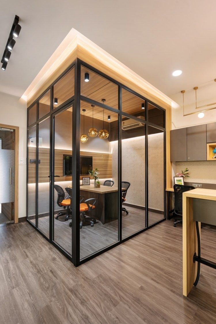 A wide-angle shot of furniture installers installing large bookshelves in a home office. The installers use levels and other measuring tools to make sure that the installation meets requirements. The bookshelves are full of books and decor, enhancing the office.