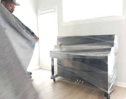 A moving truck with the Strategic Movers logo parked in front of a house, while movers are carefully unloading furniture and boxes. The scene should convey a sense of security and professionalism, with the movers wearing uniforms and using proper equipment.