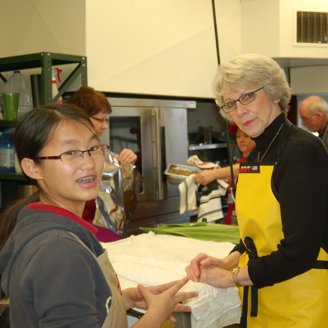 A person using a smartphone with a website displaying a volunteer sign-up form on one side, and on the other side, a food delivery app with a list of restaurants and dishes. The person is smiling and looking happy with a bright, modern background.