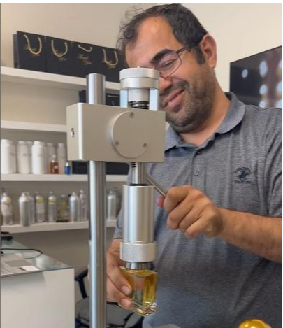 A photorealistic image of a customer at Shaar Perfume, deeply engrossed in smelling a perfume from a beautifully crafted bottle, with a variety of other perfume bottles in the background, soft lighting, and a luxurious store interior. High detail on the perfume bottle and customer's expression of contemplation and discovery.