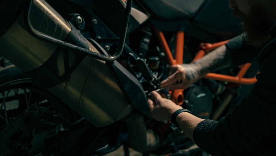A photorealistic image depicting a motorcycle receiving preventative maintenance. Focus on a mechanic checking the tire pressure, using a digital gauge. The motorcycle is clean and well-maintained. The background shows a well-lit garage, with other motorcycles undergoing service. The color palette is clean and bright, emphasizing the cleanliness and professionalism of the service. Texture details are important – the smooth rubber of the tire, the polished chrome of the wheel. Camera angle is slightly close, focusing on the mechanic's hand and the tire. The overall feel is trustworthy and reliable. 4K resolution, high quality.
