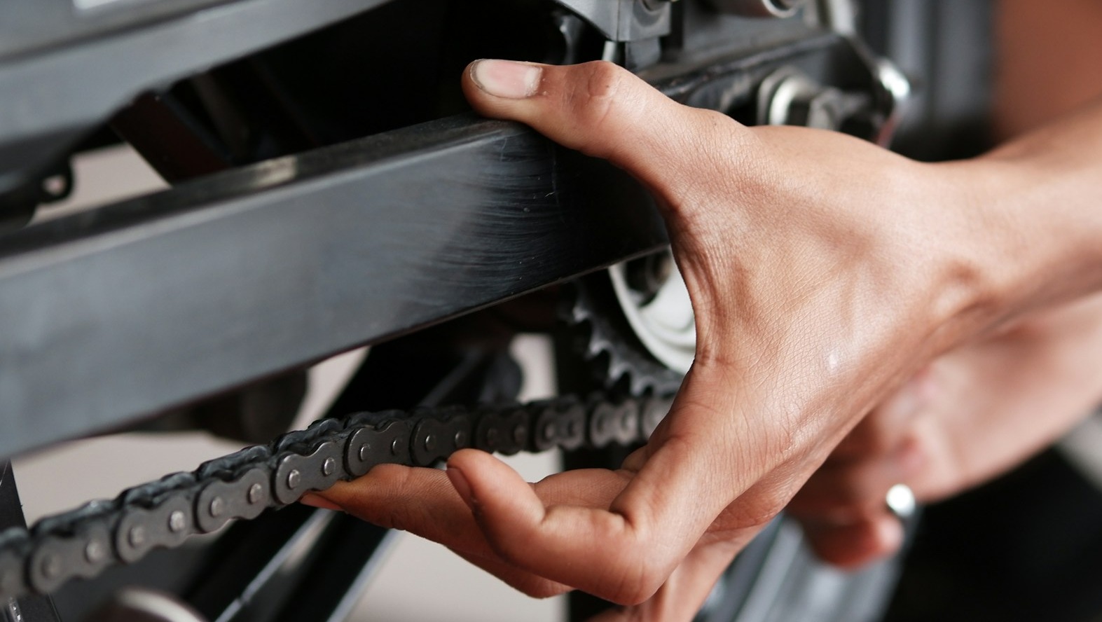 A close-up, photorealistic image showcasing the intricate workings of a motorcycle engine. Focus on a mechanic's hands, carefully using specialized tools to adjust a component. The lighting is bright and focused, highlighting the precision of the work. The color palette is metallic and industrial, with pops of color from wires and components. Emphasize texture details – the clean metal, the smooth finish of the tools, the intricate design of the engine. A shallow depth of field blurs the background, keeping the focus on the mechanic's hands and the engine. The overall feel is clean and professional. 4K resolution, sharp focus.