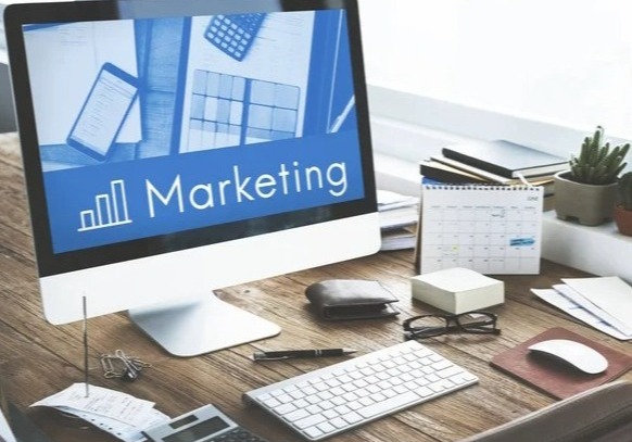 A brightly lit modern office. A young entrepreneur is smiling confidently while looking at a laptop displaying a fully customizable website builder interface. In the background, a team is collaborating on a website design project. Style: photorealistic, vibrant, showcasing a sense of ownership and control.