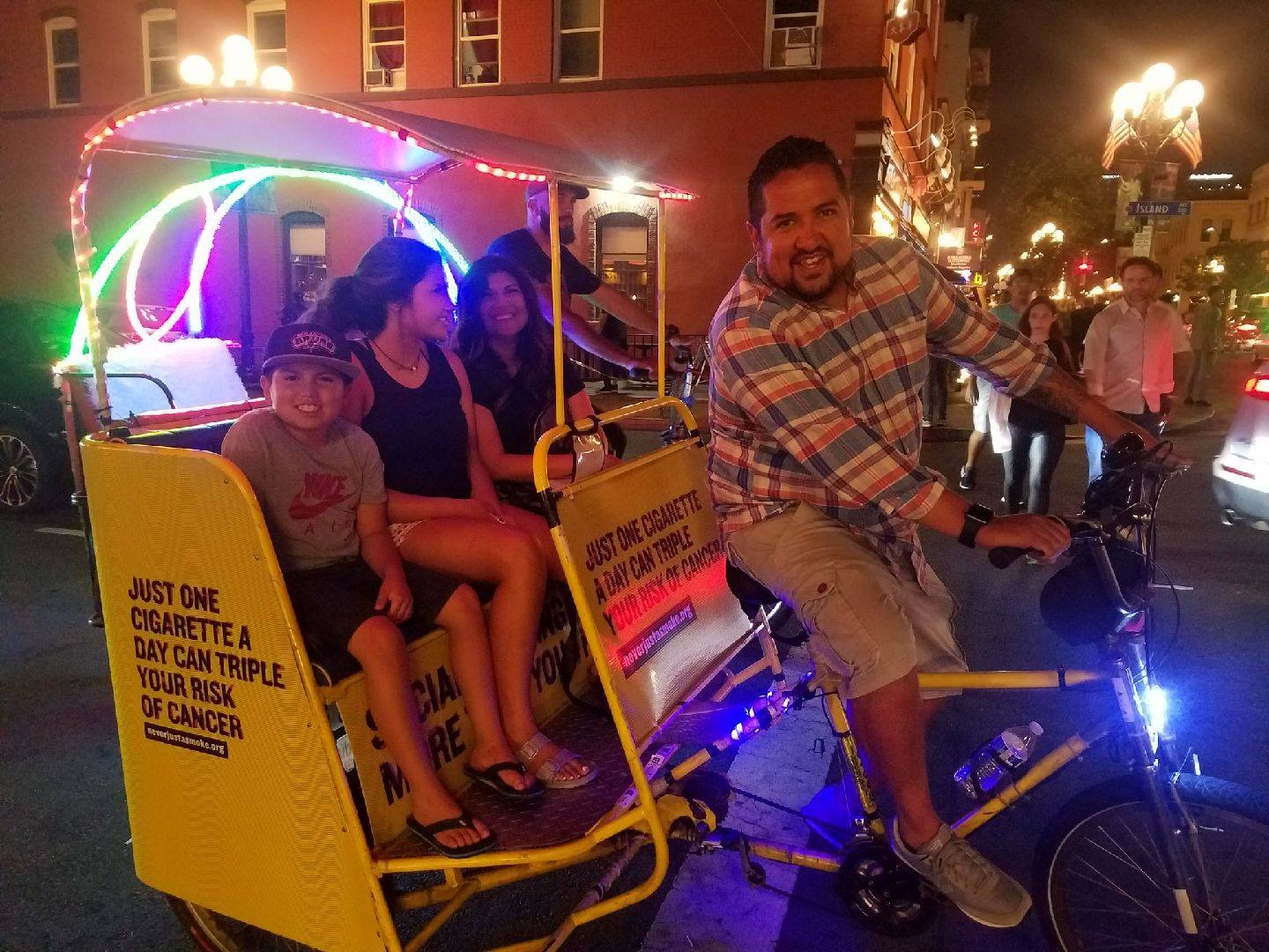 An artistic rendering of a rickshaw gliding through a lush green park in central London. The rickshaw is surrounded by trees and flowers, creating a serene and eco-friendly atmosphere. The scene should be bathed in soft, natural light, emphasizing the tranquility of the environment. The rickshaw should be depicted as blending seamlessly with nature, suggesting its minimal environmental impact. Style: Environmental art with a focus on capturing the beauty and harmony of nature.