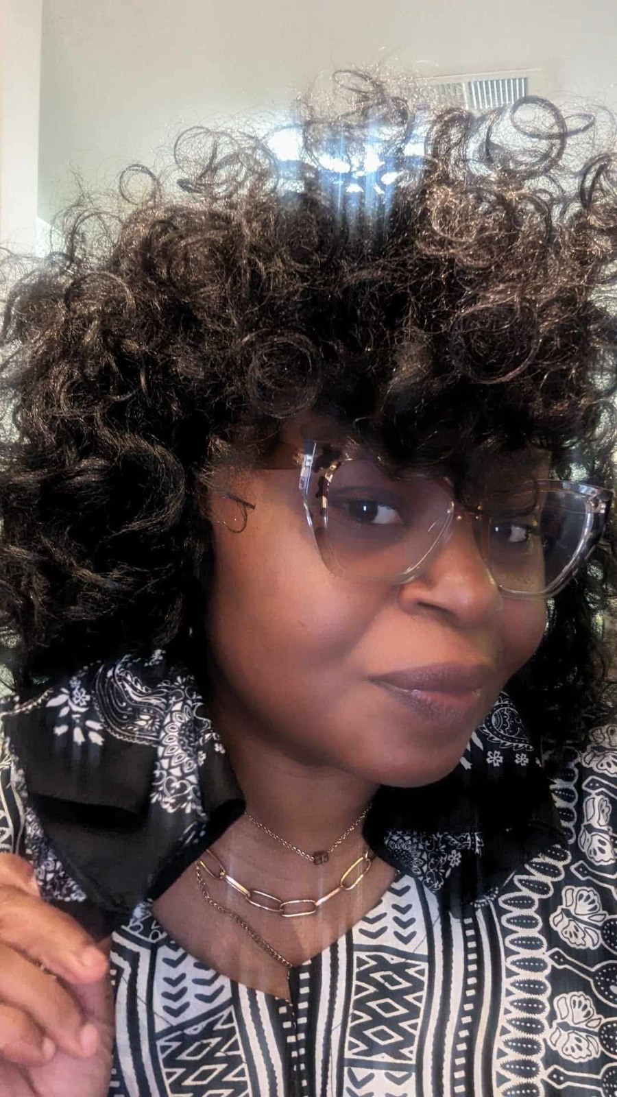 A lifestyle shot of a person wearing a pair of handmade earrings with cheerful, multicolored yarn pom-poms. The person is smiling and in a bright, sunny setting. The earrings are brightly colored and playful. The background should be a blurred-out scene, and the style of the photo should focus on creating a sense of fun and lightheartedness. Style: photorealistic, vibrant colors, lifestyle shot