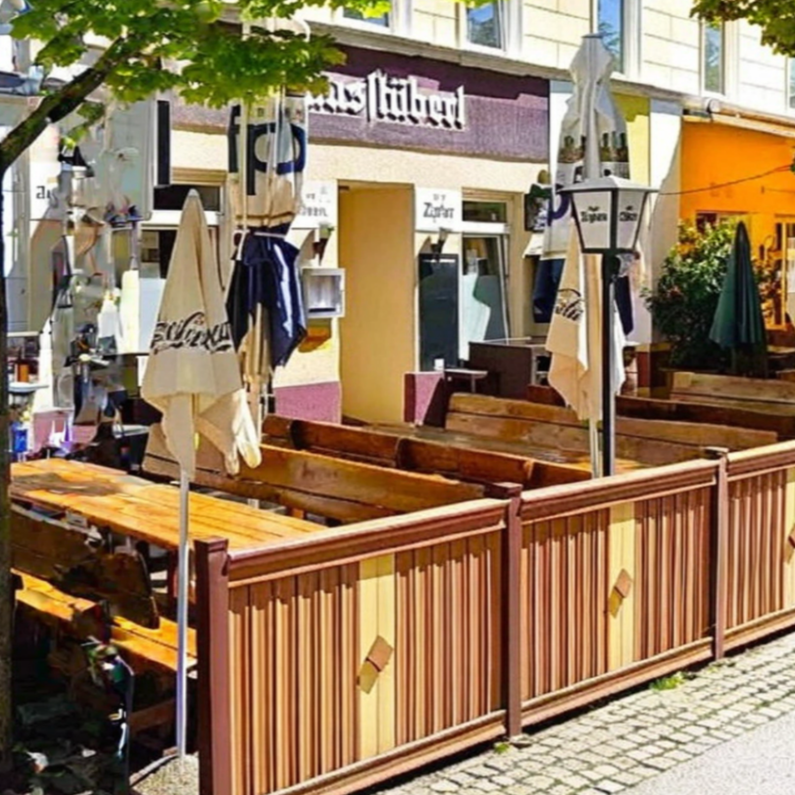 A wide-angle shot of the terrace featuring heavy wooden tables and benches with Austrian-inspired designs. Include details like traditional tablecloths and decorations.