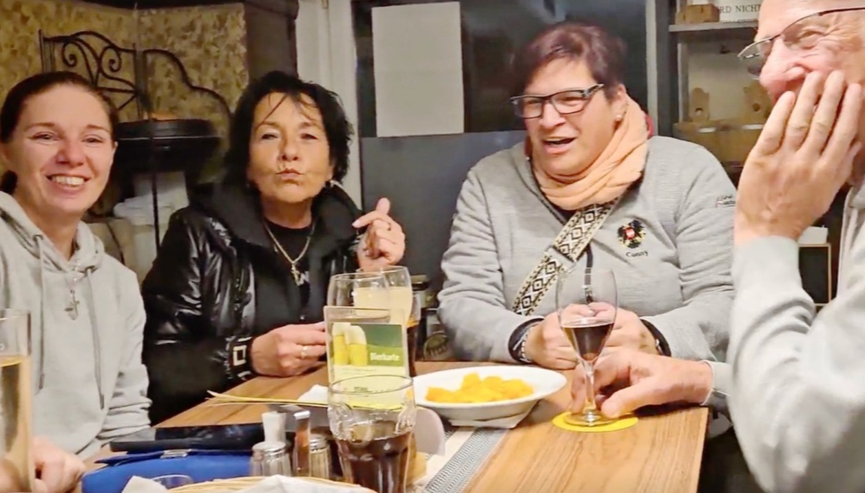 A wide shot, the staff engaging in meaningful interaction with local customers. The scene is lit to produce a feeling of warmth.