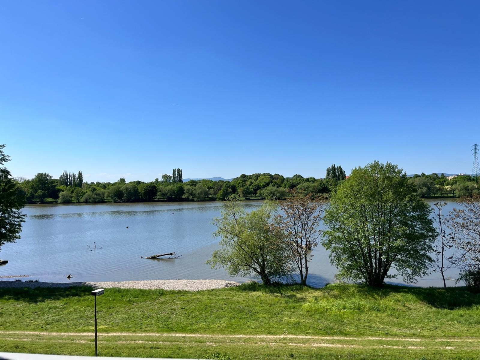 Create a photorealistic image showcasing the outside of a group of apartments situated directly on a beach. The apartments should be modern and elegant, with a clean design and plenty of natural light. The beach should be sandy and inviting with the ocean visible in the background.