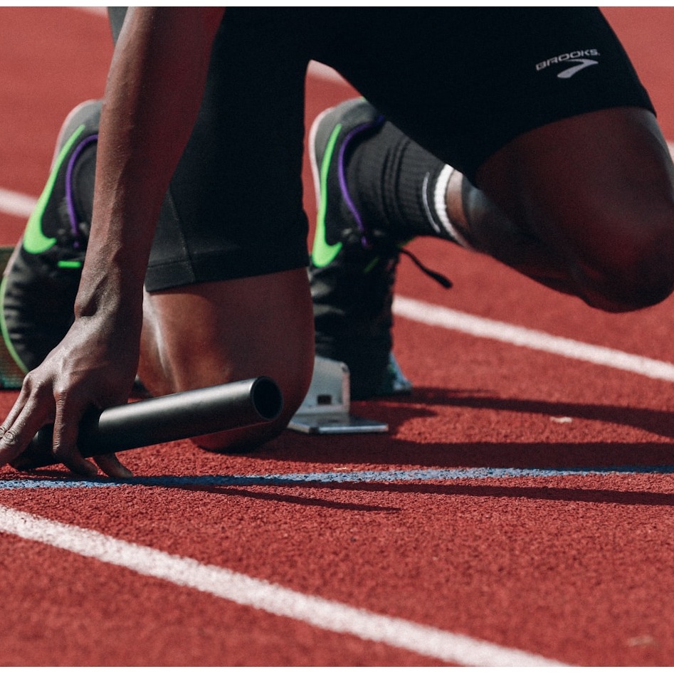 A vibrant middle-aged professional bursting with energy while jogging through a sun-dappled park during golden hour. She wears athletic gear and has a natural, radiant glow with perfect form. In the background, a nutritionist holds a tablet showing personalized meal plans while a fitness tracker on her wrist displays optimal heart rate data. The scene should capture dynamic movement with motion blur in the foliage, emphasizing vitality through strong composition, rich colors, and the subject's evident joy and physical capability in her prime health.