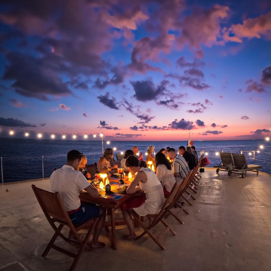 A stylized, whimsical image depicting a wedding ceremony taking place on the deck of the Beauport yacht, surrounded by stunning scenery. Use bright, romantic colors and artistic effects.