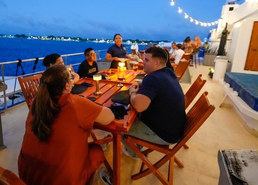 A photorealistic image of a corporate event taking place on the yacht. Focus on showcasing professional interactions in a luxury setting, with modern features of the boat in the background.