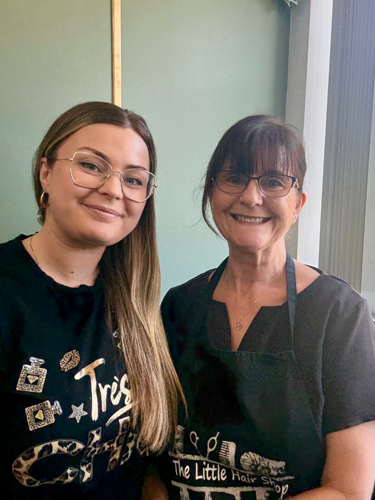 A photorealistic image that captures the essence of The Little Hair Shop’s mission. The scene portrays a happy stylist engaging with a client in a vintage-style salon, surrounded by lush plants and elegant decor. The lighting is bright and inviting, with a soft focus that enhances the warm colors of hair products on display. The composition showcases a friendly and welcoming environment, emphasizing diversity among clients. Style reference: rustic with a modern flair. Technical specs: 4K resolution, high quality.