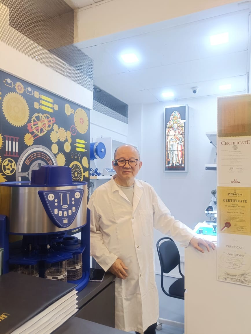 Asian watchmaker examining a mechanical movement with precision tools