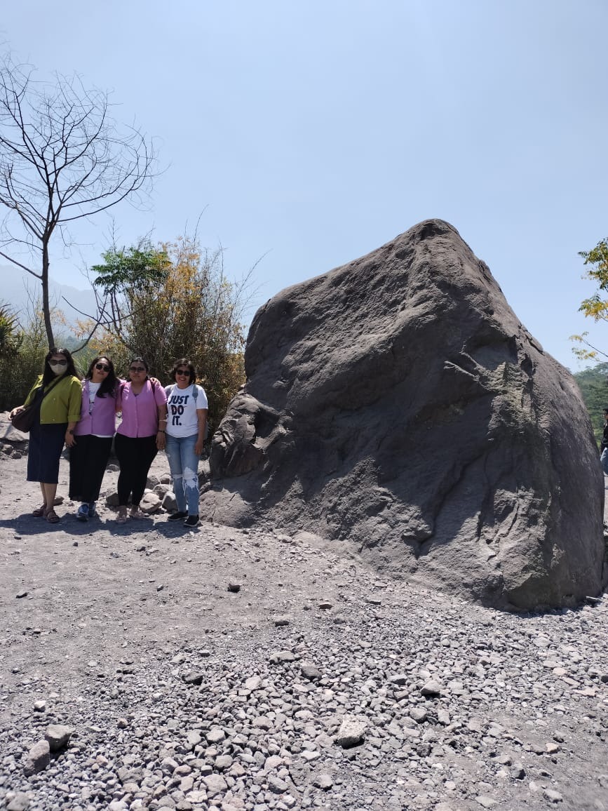 A dynamic and energetic image capturing the excitement of Jeep racing on off-road trails near Mount Merapi. The focus should be on the Jeep kicking up dust and gravel as it navigates steep slopes. The background features blurred greenery and volcanic rocks, creating a sense of speed. Shimmering sunlight highlights the dust particles, adding to the thrilling atmosphere. The angle should evoke motion, with a wide field of view that showcases the rugged landscape, capturing the thrill and adventure of the journey.
