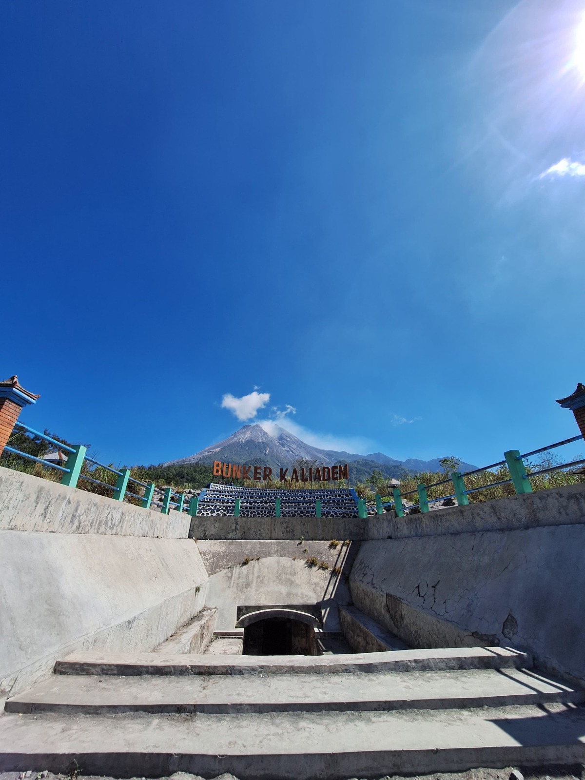 A dynamic and energetic image capturing the excitement of Jeep racing on off-road trails near Mount Merapi. The focus should be on the Jeep kicking up dust and gravel as it navigates steep slopes. The background features blurred greenery and volcanic rocks, creating a sense of speed. Shimmering sunlight highlights the dust particles, adding to the thrilling atmosphere. The angle should evoke motion, with a wide field of view that showcases the rugged landscape, capturing the thrill and adventure of the journey.