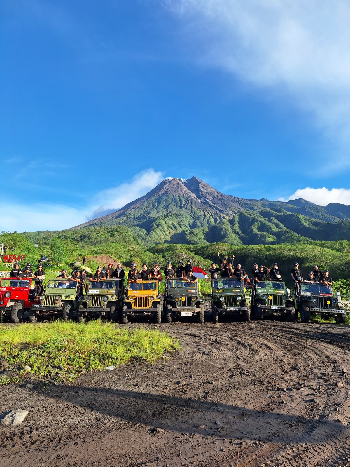 A thrilling image showing the excitement of tourists inside the Jeep as they navigate through challenging terrain. The expressions of joy and amazement on their faces should be captured beautifully, with the rugged landscape of Mount Merapi visible through the Jeep's windows. The lighting should be bright and lively, highlighting the adventurous spirit of the tour. Surrounding elements like dust clouds and volcanic rocks should add depth and context to the scene. The image needs to be photorealistic, focusing on conveying the thrill of adventure.