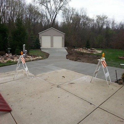 A photorealistic image showing a well-constructed concrete parking lot outside a bustling commercial building. Include visible parking lines and clear signage. Use neutral colors and bright lighting to emphasize functionality and safety.
