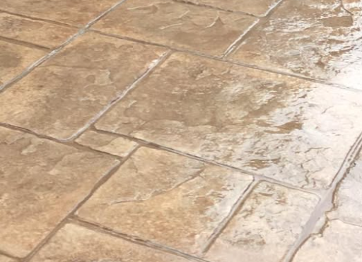  Create a photorealistic close-up shot of decorative stamped concrete patio with an intricate stone-like pattern. The patio is furnished with comfortable outdoor seating. Use soft, natural lighting and a warm color palette to convey a sense of relaxation and beauty.