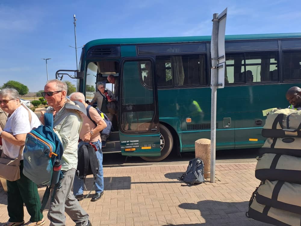  Create a photorealistic image showing a lush forest with sunlight filtering through the trees. In the foreground, a group of travelers are participating in a reforestation project, planting saplings. The image should convey a sense of harmony between nature and human activity. The lighting should be soft and ethereal, creating a peaceful and serene atmosphere. The color palette should be dominated by greens and browns, with pops of color from the wildflowers and the travelers' clothing. The overall style should emphasize the importance of sustainable travel and the preservation of the environment.