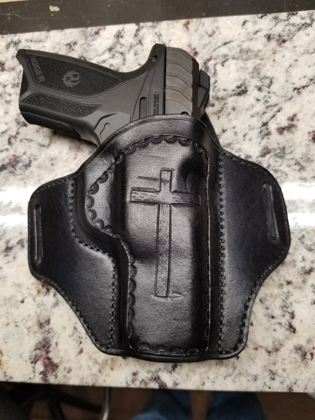 Create a photorealistic image of a meticulously crafted leather holster, perfectly molded to the shape of a pistol. The holster should be displayed against a clean, dark background to highlight its intricate details. Focus on the stitching, the leather grain, and the overall craftsmanship. The lighting should be dramatic and focused, emphasizing the holster's contours. Style reference: High-end product photography, emphasizing texture and form.