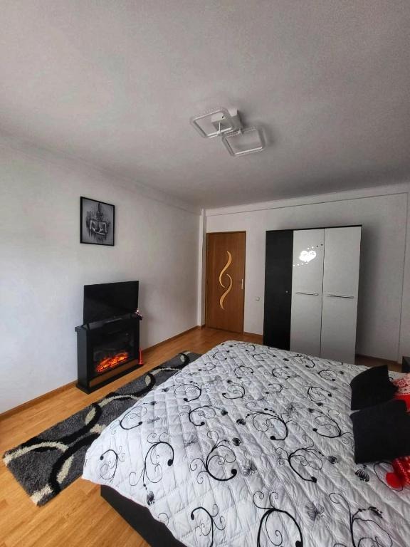 Depict the living room in "Casa cu 2 Dormitoare La Simo". Capture traditional Romanian decorative elements, such as hand-woven carpets, pottery, and wooden carvings. A fireplace adds a cozy touch. The color palette is warm and earthy, with reds, browns, and oranges dominating the scene. Soft light filters through the windows, creating a comfortable and inviting atmosphere. Focus on the textures of the fabrics, wood, and ceramics. The camera angle is medium, showcasing the entire room. The image should evoke a sense of cultural heritage and warmth. Aim for a photorealistic, high-quality image.