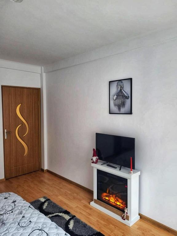 Create a photorealistic image that encapsulates the essence of "Casa cu 2 Dormitoare La Simo". The scene should be a warmly lit interior view of the living room. A comfortable sofa with traditional Romanian cushions should be the focal point. A crackling fireplace adds to the cozy atmosphere. On the coffee table, place a few Romanian story books, and a steaming cup of tea. The overall style should reflect rustic charm, with wooden beams and hand-woven rugs. Capture the texture of the wool, wood, and the flames in the fireplace. The lighting should be soft and inviting, enhancing the feeling of home. Camera angle should be medium, conveying a sense of spaciousness and warmth. Aim for a 4K resolution, high-quality image with hyperrealistic details to emphasize the comfort and authenticity of the space.