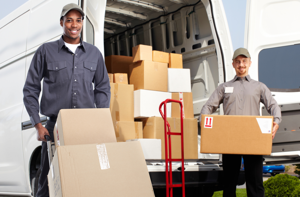 A photorealistic image showcasing two movers carefully unloading and unpacking boxes into a new, well-lit home.  Show items such as furniture and boxes being placed precisely in rooms and attention to unpacking fragile items. The movers should be friendly and efficient, while the background shows a clean and welcoming new home environment.