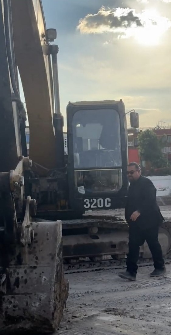 Create a stylized image depicting a compass pointing towards a modern apartment building, symbolizing guidance and direction in the real estate process. The compass should be gold and elegantly designed. The apartment building should be located in a vibrant neighborhood in Mexico City, with colorful architecture and lush greenery. The background should feature a clear blue sky and a gentle breeze. The overall composition should convey a sense of clarity, trust, and reliability. Use a shallow depth of field to focus on the compass, with the apartment building slightly blurred in the background. The style should be clean, modern, and sophisticated. Aim for 8K resolution and hyperrealistic detail.