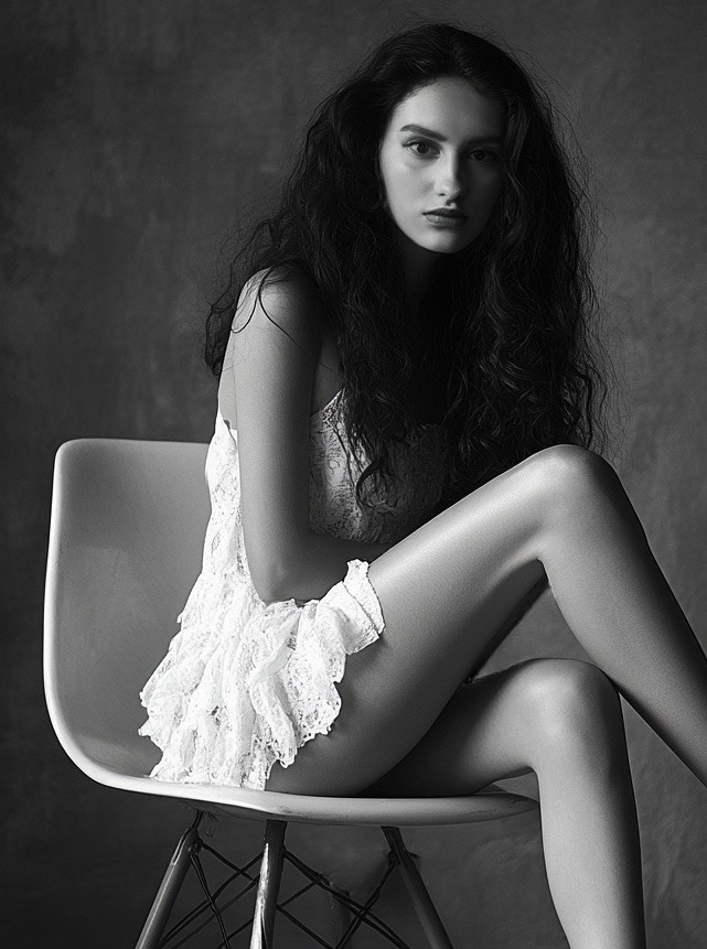 A photorealistic, ultra-high quality 8K image depicting a vibrant, swirling galaxy contained within a minimalist, futuristic geometric structure. The structure should be constructed from polished chrome and glowing neon accents. Within the galaxy, abstract representations of art, sound waves, and wellness symbols float serenely. The color palette is a blend of deep blues and purples contrasted with bright, playful oranges and yellows. The lighting is soft and ethereal, casting gentle reflections on the chrome surfaces. Camera angle is a high-angle shot, capturing the immensity of the galaxy within the structure. Textures should be rich and detailed, emphasizing the contrast between the cosmic chaos and the structured design. The environment is a void of space, allowing the subject to stand out. Style reference: blending the geometric abstraction of Hilma af Klint with the futuristic minimalism of Syd Mead. Hyperrealistic details are crucial.