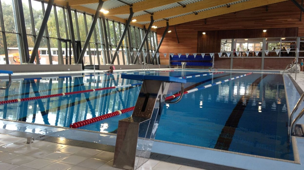 A photorealistic image depicting a calm and secure indoor swimming pool environment. Focus on the shallow end of the pool, with clear, inviting water. Soft, natural lighting creates a sense of safety and tranquility. The background features colorful, playful elements that are age-appropriate. The image should evoke a feeling of comfort and security, highlighting the ideal setting for learning to swim. Camera angle should be slightly above, looking down into the pool.
