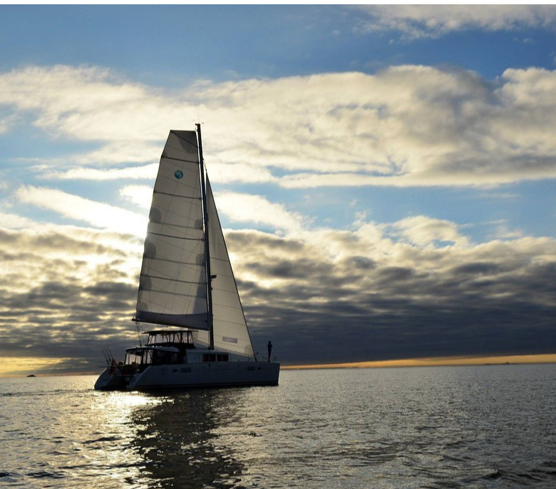 Create an image of a luxurious yacht fully equipped for an exquisite Arctic cruise. Showcase outdoor dining areas with elegant table settings, plush sun loungers, and a panoramic view of the stunning Arctic scenery. Add vibrant flowers or decorative elements to convey a sense of elegance. The waters around the yacht should be calm and reflect the hues of a beautiful sunset. Aim for photorealistic quality, ensuring textures of the yacht’s materials and furnishings are detailed and appealing.