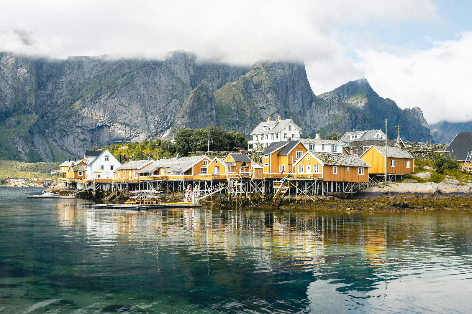 Create a photorealistic, ultra-high quality header image capturing the essence of 'Arctic Cruise in Norway AS'. The composition features a majestic Arctic cruise ship navigating through serene waters, flanked by towering snow-capped mountains illuminated by the soft glow of the Arctic sun. The foreground includes icy blue waters reflecting the sky, while the background presents a breathtaking panorama of dramatic cliffs and quaint fishing villages. The lighting is golden hour, casting warm hues of orange and pink across the scene. Textures should exhibit the rough surfaces of ice and the smooth finish of the ship, enhancing the hyperrealistic quality of the image. Aim for 8K resolution, showcasing the stunning details of this Arctic landscape.