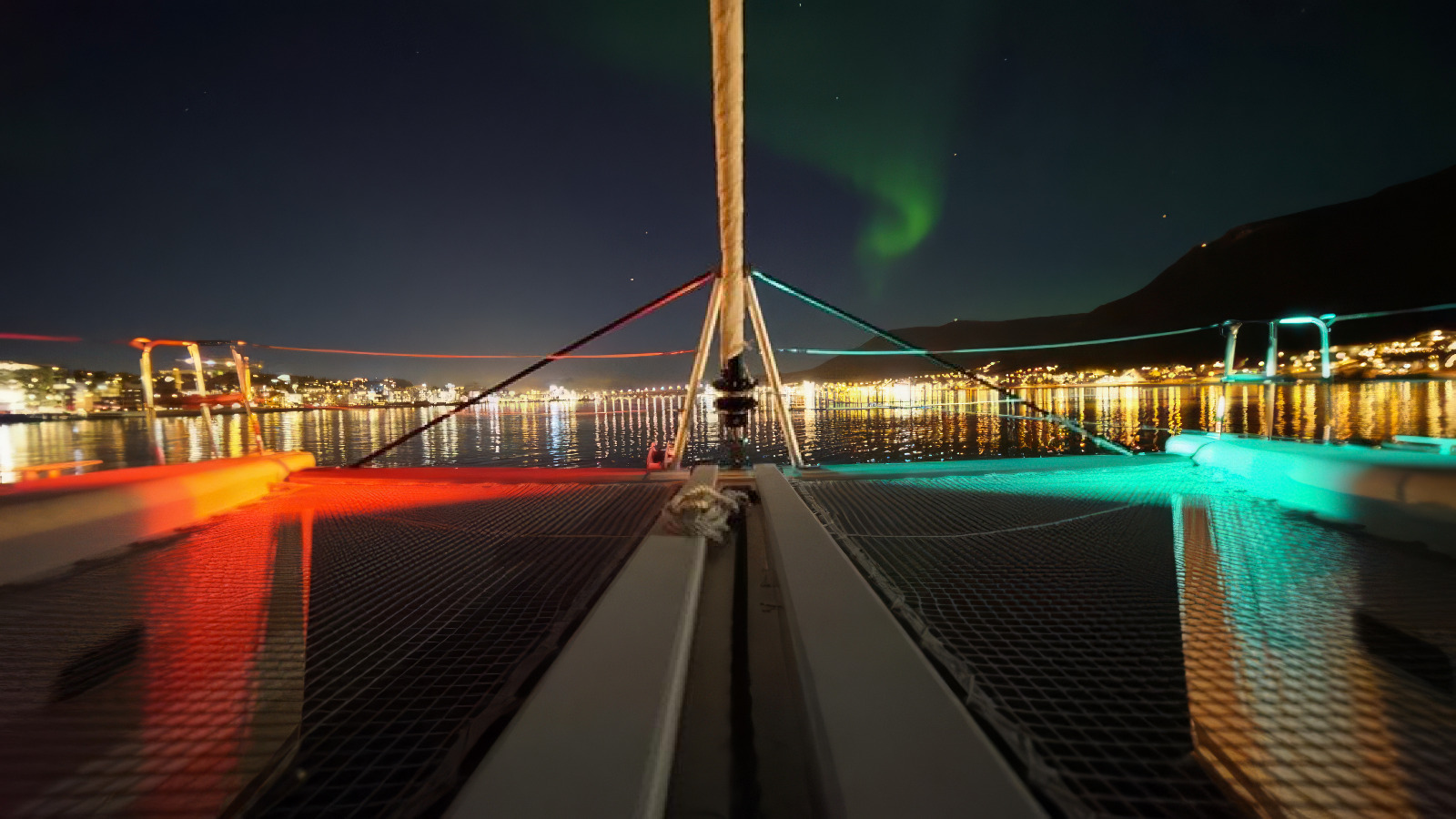 Formulate an image that features cultural engagement with locals in Senja. Display a friendly interaction between travelers and local artisans, perhaps at a market or cultural site. Include traditional Norwegian attributes such as crafts, clothing, or food. The background should show the natural beauty of Senja, with the mountains providing a scenic backdrop. Incorporate warm, inviting tones depicting the essence of community and culture. The image should be photorealistic, emphasizing rich textures and colors, crafted in high definition.