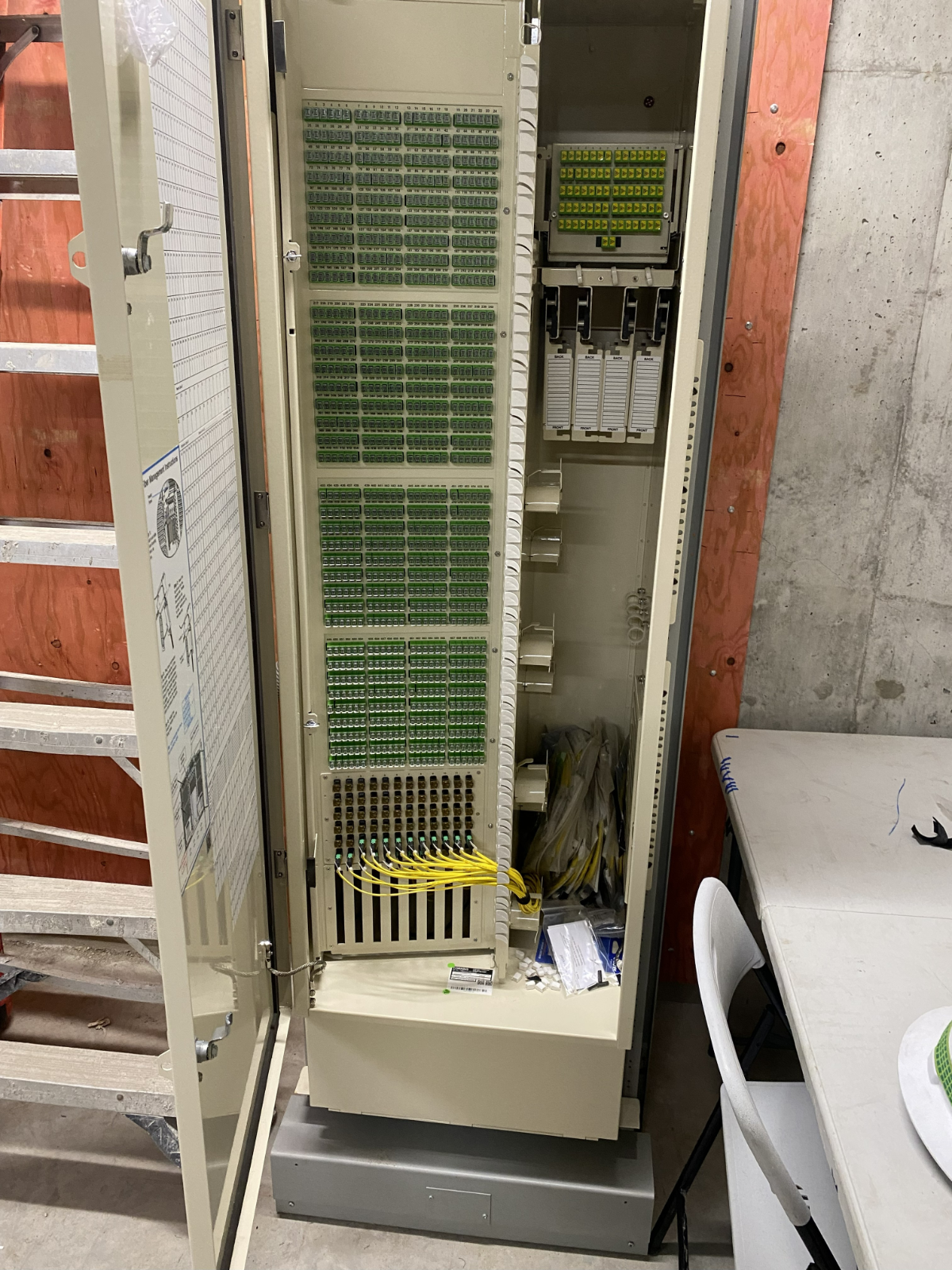 A photorealistic image depicting a technician troubleshooting a fiber optic connection using a light source and fiber identifier. The image should convey a sense of problem-solving and technical expertise. Style: Practical, informative, and focused.