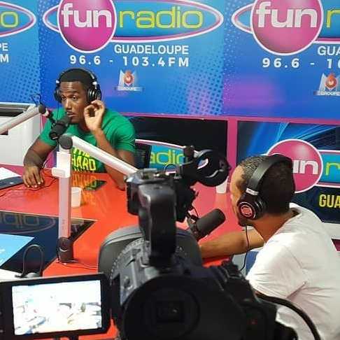 A dynamic reporting scene set in a bustling market, showcasing a journalist interviewing a local vendor. The lighting is natural, with bright sunlight illuminating the colorful produce stalls, creating a lively and authentic atmosphere. The camera angle is slightly tilted for a more engaging perspective, focusing on the interaction between the journalist and the vendor. The color palette is vibrant, showcasing a variety of fruits and vegetables, with earthy tones reflecting the market's ambiance. Textures of fabric and materials used in the market stalls add depth to the image. Environmental elements include curious onlookers and traditional market signs, enriching the narrative of community commerce. The style draws inspiration from photojournalism, capturing real-life candid moments in ultra-detail, perfect for storytelling in 8K resolution.
