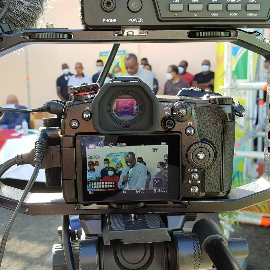 A vibrant wedding scene captured in ultra-high quality, showcasing a joyous couple exchanging vows under a beautifully decorated arch. The scene is filled with colorful floral arrangements and soft diffused lighting, creating an enchanting mood. The camera angle is slightly elevated, providing a sweeping view of guests smiling and celebrating. The color palette includes pastel shades, with hints of bright flowers contrasting against an azure sky. The texture of the bridal gown is detailed, shimmering with intricate lace patterns. Environmental elements include nature with lush greenery surrounding the area, enhancing the romantic atmosphere. Props like champagne glasses held by delighted guests add a festive touch. This image is designed in the style of renowned wedding photographers, achieving 8K resolution and hyperrealistic detail, ensuring every joyful expression is captured.